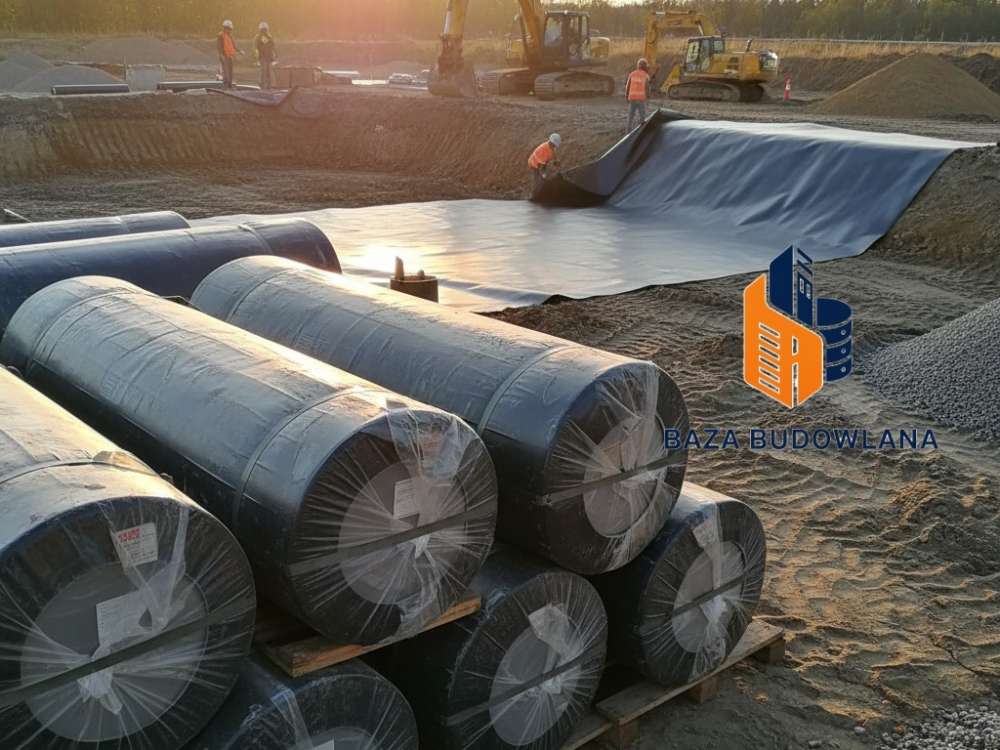 Czarna geomembrana HDPE rozkładana na gruncie jako szczelna bariera syntetyczna w inżynierii geotechnicznej.