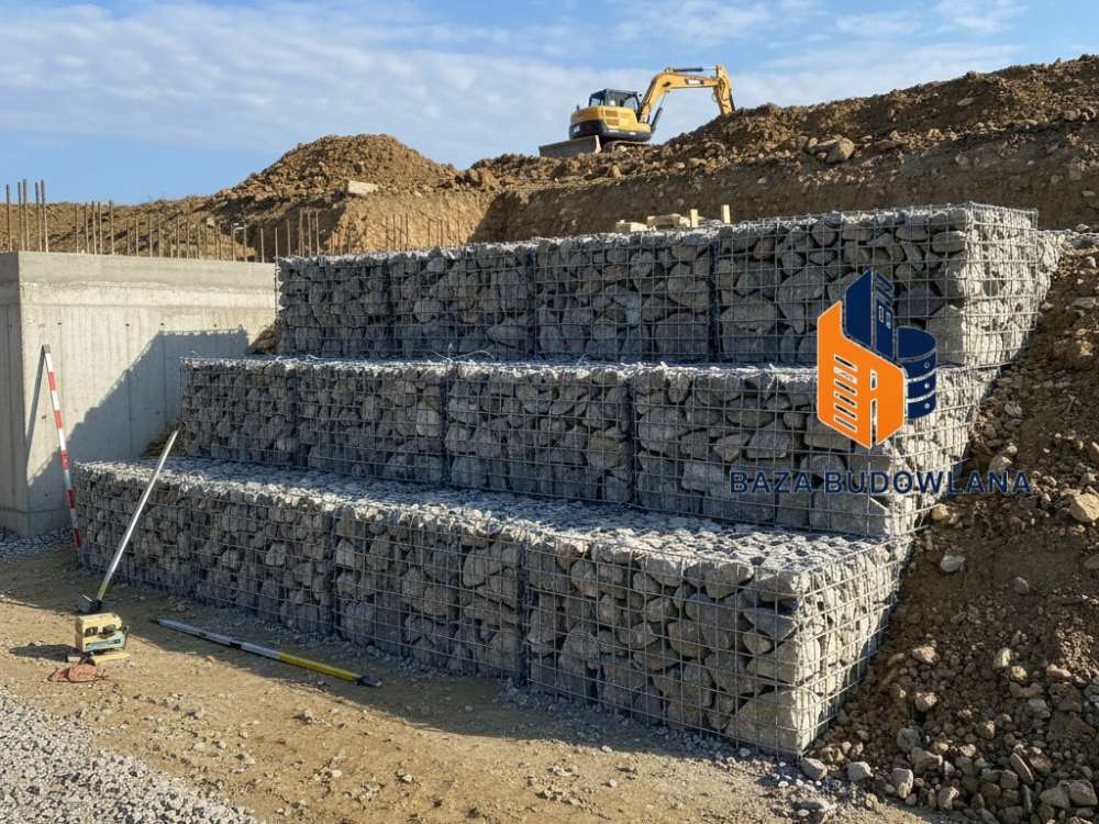 Kosze gabionowe wypełnione kamieniami jako ciężkie zabezpieczenie oporowe stabilizujące skarpę.